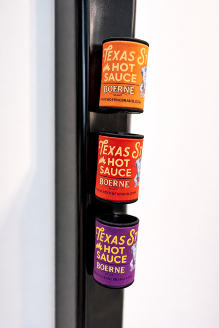 Boerne Brand Texas Style Hot Sauce koozies attached to a refrigerator